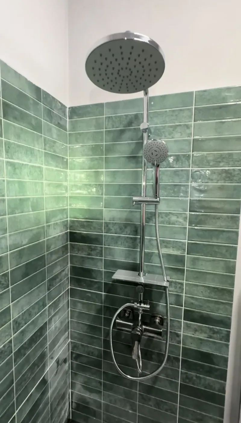Duș cu pară mare de tavan, montat pe perete cu faianță verde