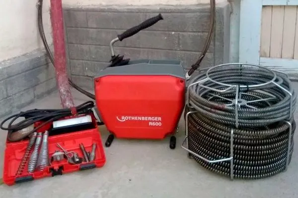 Mașină electrică de desfundat, roșie, lângă spirale și capete de tăiere